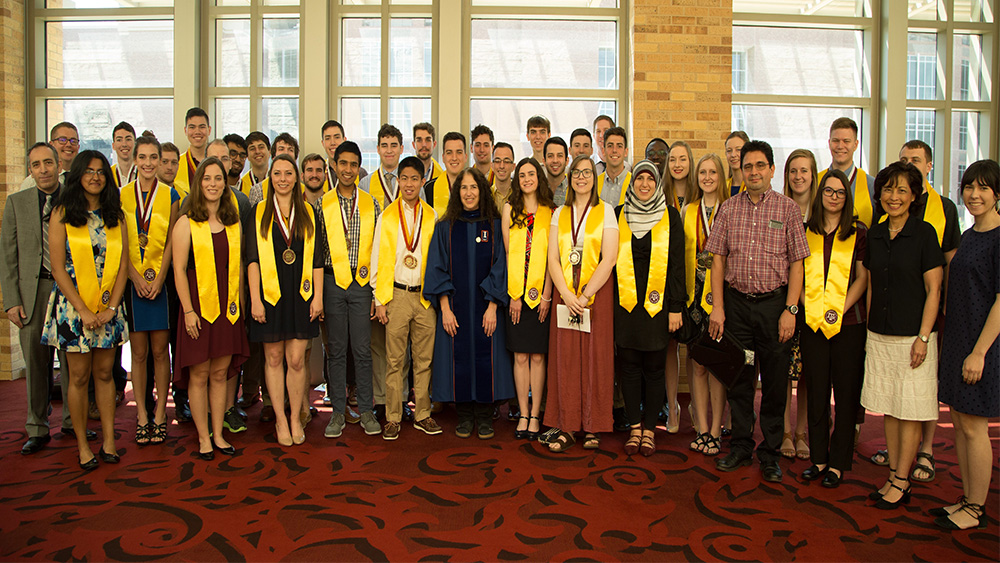 一群毕业的工程荣誉学生戴着毕业礼服摆姿势拍照。