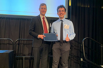 Dr. Schaefer presenting Eric Nunes with the Peer Teacher Excellence Award on stage.