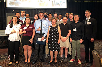 Group of peer teachers and their advisor Dr. Leyk standing in front of a stage after the spring banquet.