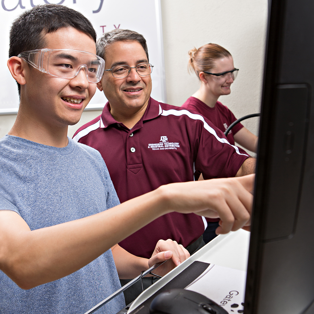 教员和两个学生看着电脑屏幕