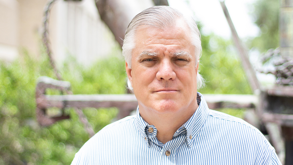 Thomas Blasingame站在德州农工大学理查森大楼外的钻工雕像前