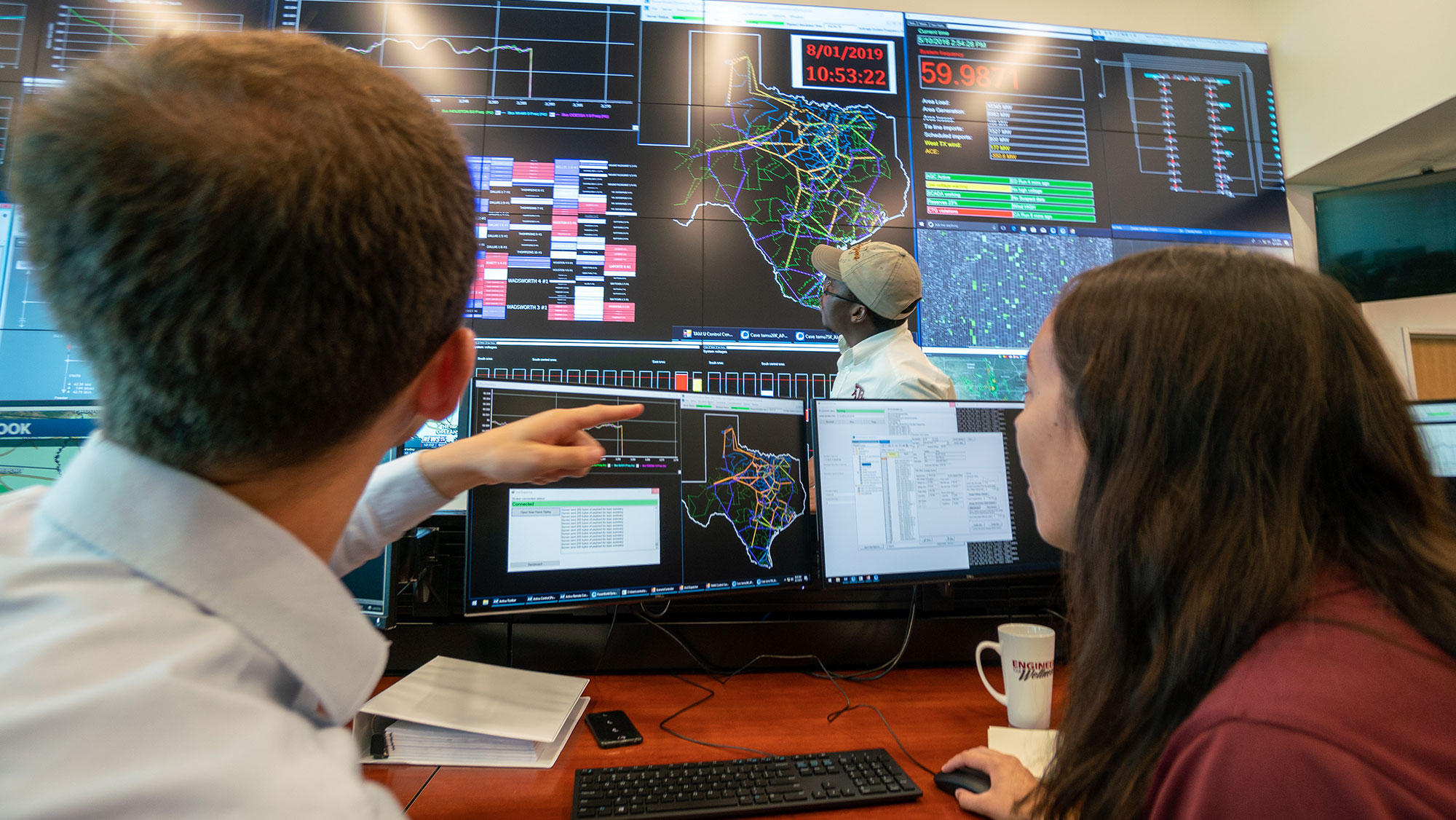 Electrical and Computer Engineering students looking at a smart grid in a lab.