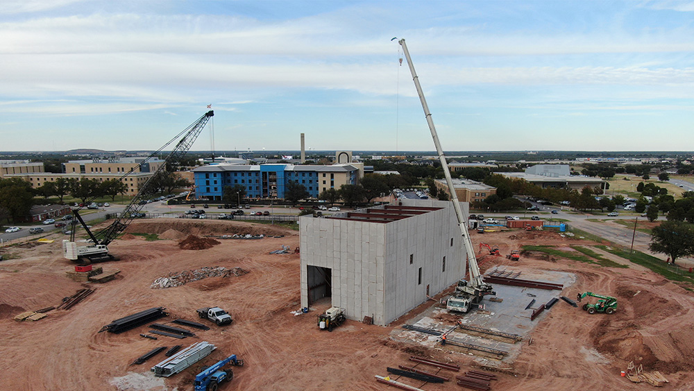 Aerial view of construction crane hoisting material inside concrete facility on at Gayle and Max Dillard Science Engineering Research Center on the Abilene Christian University campus.